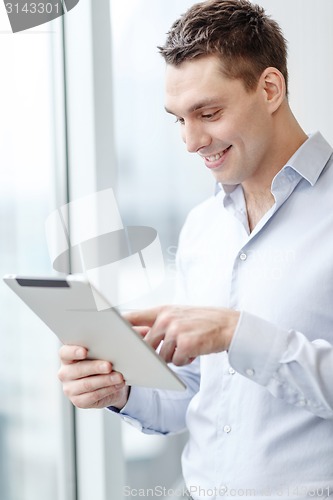 Image of smiling businessman with tablet pc in office