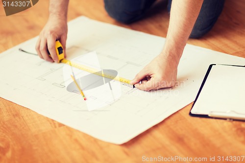 Image of close up of male hands measuring blueprint