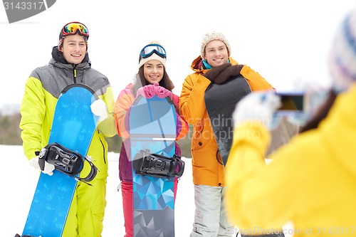 Image of happy friends with snowboards and smartphone