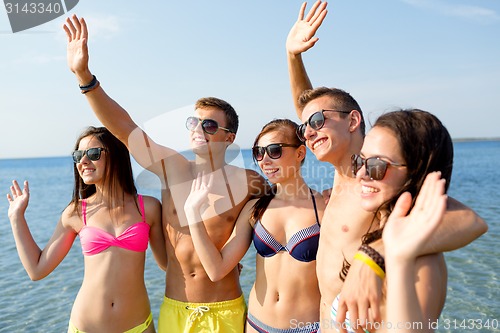 Image of smiling friends in sunglasses on summer beach