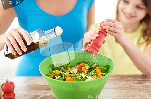 Image of close up of happy family cooking salad in kitchen