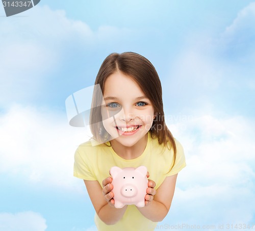 Image of beautiful little girl with piggy bank