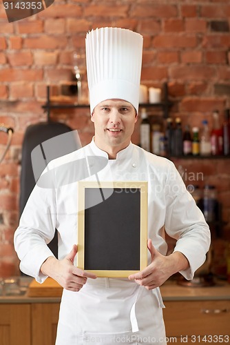 Image of happy male chef with blank menu board in kitchen