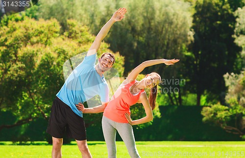 Image of smiling couple stretching outdoors
