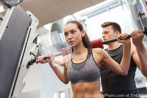 Image of man and woman with barbell flexing muscles in gym