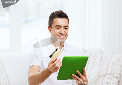 Image of smiling man working with tablet pc at home