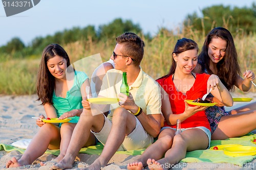 Image of smiling friends sitting on summer beach