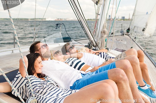 Image of smiling friends lying on yacht deck