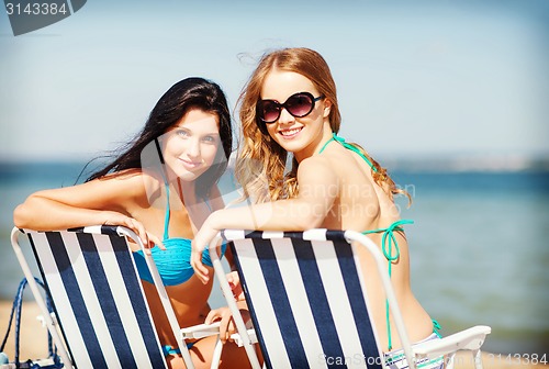 Image of girls sunbathing on the beach chairs