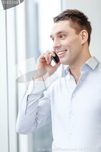 Image of smiling businessman with smartphone in office
