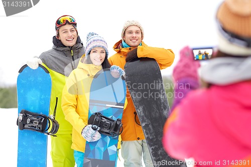 Image of happy friends with snowboards and smartphone