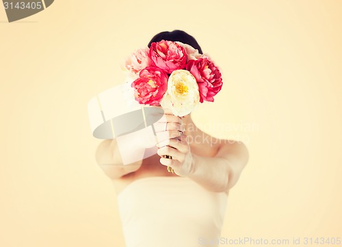 Image of woman holding bouquet of flowers over her face