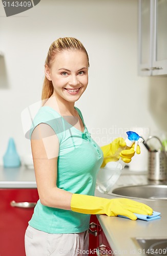 Image of happy woman cleaning table at home kitchen