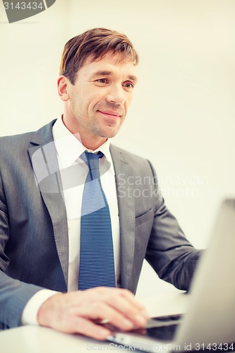Image of businessman with laptop in office