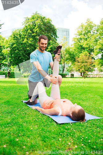 Image of smiling couple stretching outdoors