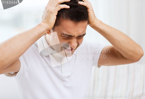 Image of unhappy man suffering from head ache at home