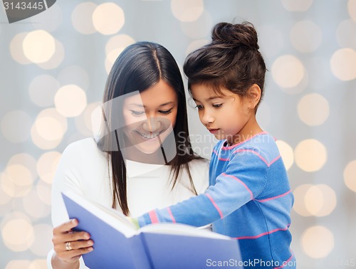 Image of happy mother and daughter reading book