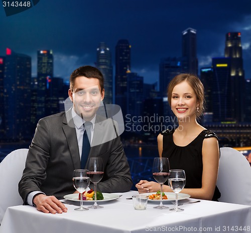 Image of smiling couple eating main course at restaurant