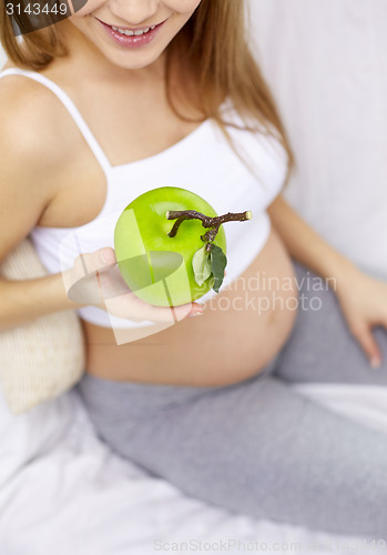 Image of close up of pregnant woman eating apple at home