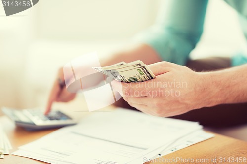 Image of close up of man counting money and making notes