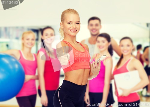 Image of smiling sporty woman with smartphone