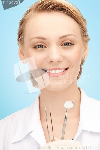 Image of happy young female dentist with tools