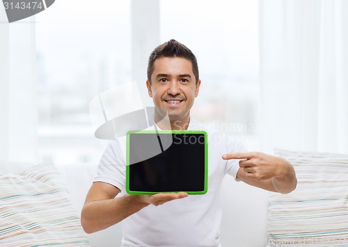 Image of smiling man showing tablet pc blank screen at home