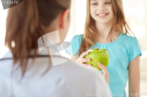 Image of close up of doctor giving apple to happy girl