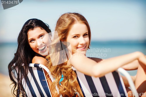 Image of girls sunbathing on the beach chairs