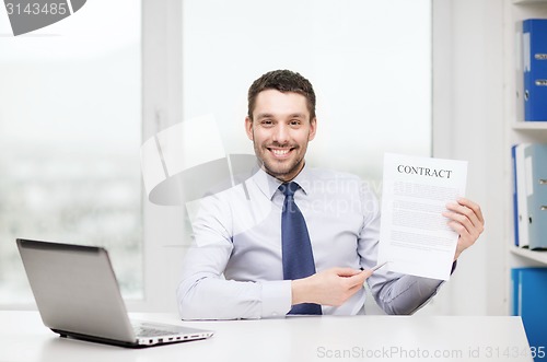 Image of businessman with laptop and contract at office