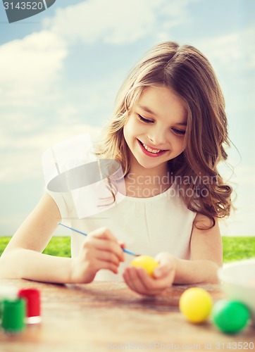 Image of smiling little girl coloring eggs for easter