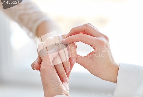 Image of close up of lesbian couple hands with wedding ring