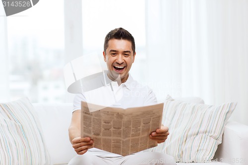 Image of happy man reading newspaper and laughing at home