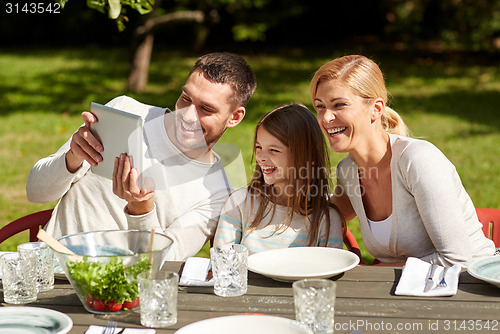 Image of happy family with tablet pc at table in garden