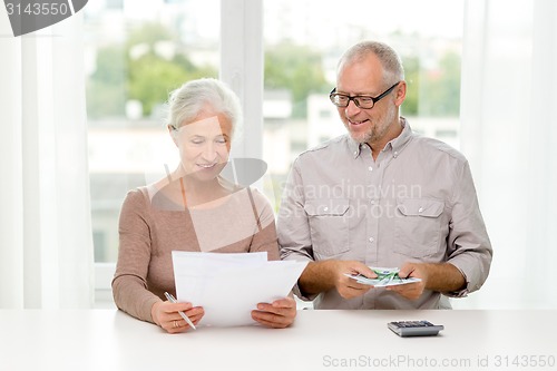 Image of senior couple with money and calculator at home