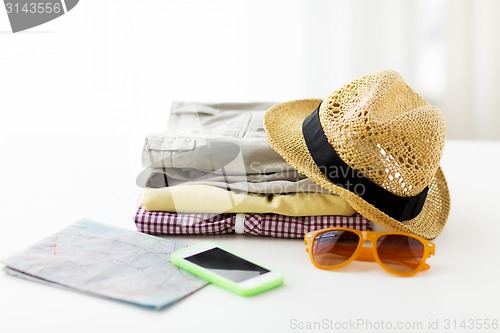 Image of close up of summer clothes and travel map on table