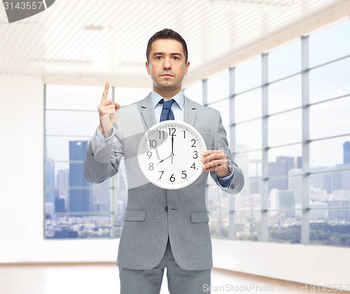 Image of businessman in suit holding clock with 8 o'clock