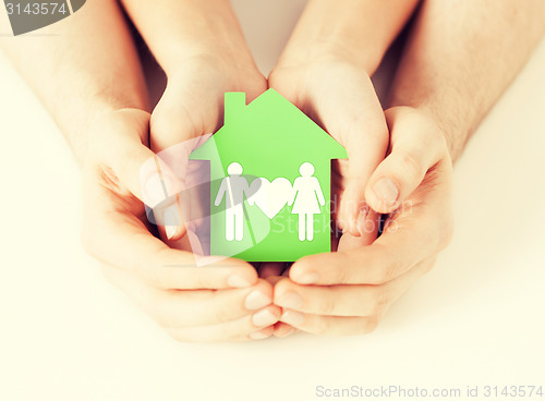 Image of hands holding green house with family