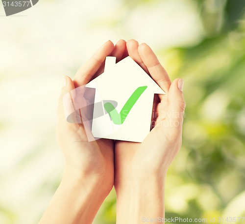 Image of hands holding house with check mark