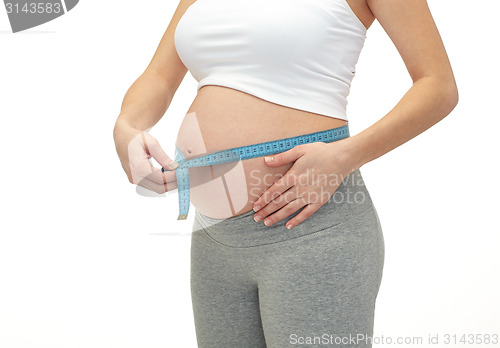 Image of close up of pregnant woman measuring her tummy