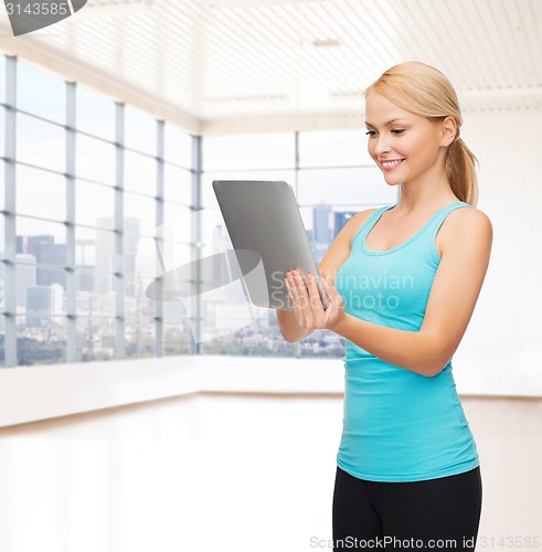 Image of smiling woman with tablet pc in gym