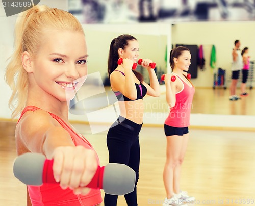 Image of smiling beautiful sporty woman with dumbbell