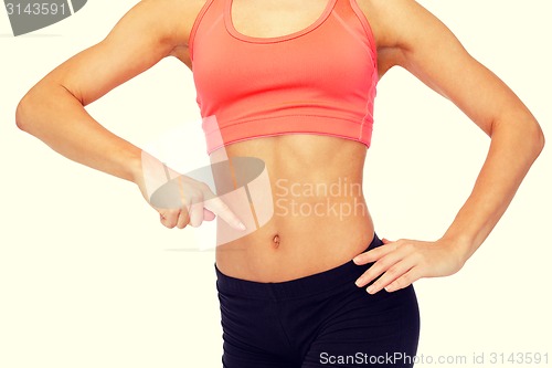 Image of close up of woman pointing finger at her six pack