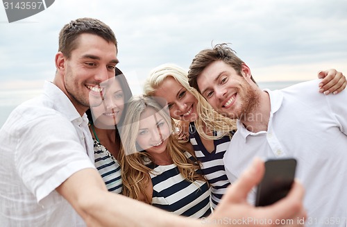 Image of happy friends on beach and taking selfie