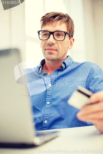 Image of man with laptop and credit card at home