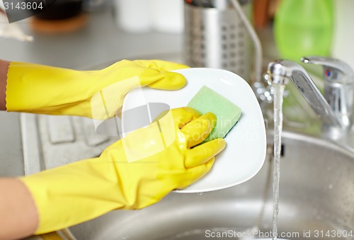 Image of close up of woman hands washing dishes in kitchen