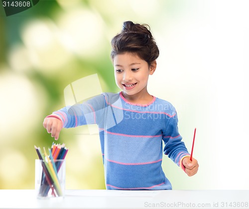 Image of happy little girl drawing with coloring pencils