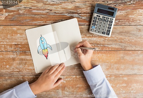 Image of close up of hands with calculator and notebook