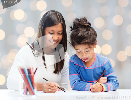 Image of happy mother and daughter drawing with pencils