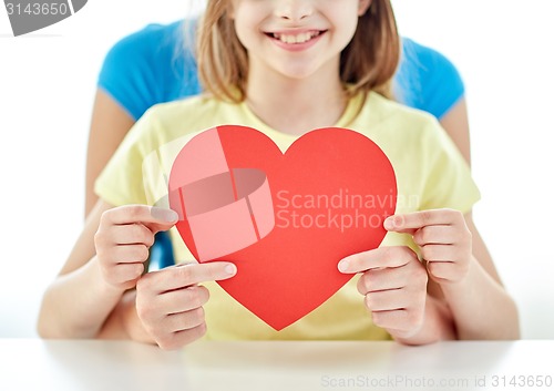 Image of close up of girl and mother holding red heart